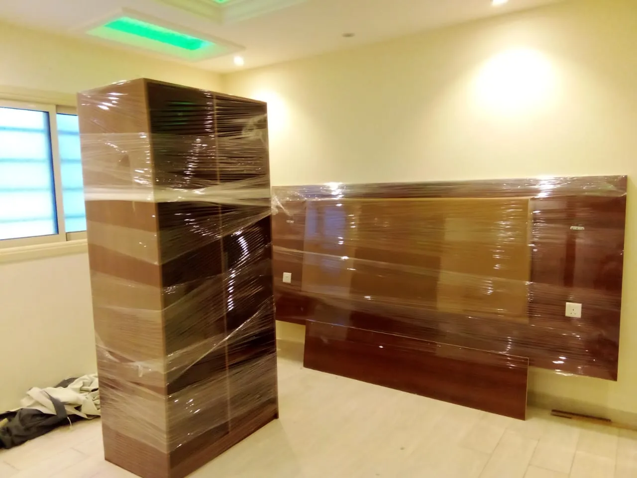 خزانة ولوح سرير مغلفان بالنايلون الشفاف في غرفة نوم